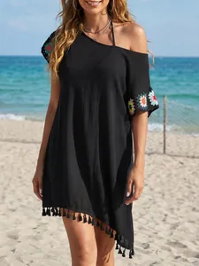 Boho-Strandkleid in Schwarz mit bunten Häkelblumen und Fransen am Saum für Damen am Strand
