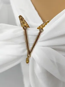 Detailed view of golden V-shaped metal buckle on white chiffon beach wrap shawl