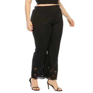Detail view of black plus size trousers featuring an intricate laser-cut floral hem design