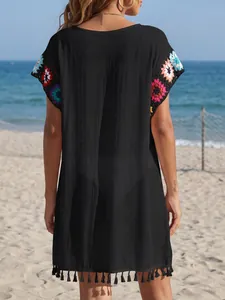 Rückansicht eines schwarzen Strandkleides mit Häkelärmeln und Fransen am Saum