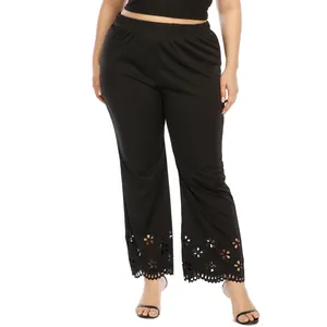 Detail of plus size black trousers with laser-cut floral pattern at the hem.