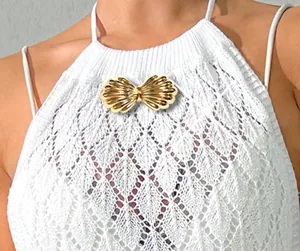 Gros plan d'une boucle décorative en métal doré en forme de coquillage sur une robe de plage.