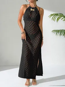Détail d'une robe de plage noire au crochet avec dos nu et boucle en coquillage