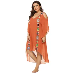 Detalle de un vestido de playa naranja de talla grande con bordes florales de ganchillo.