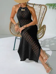 Détail d'une robe de plage en crochet noir avec une boucle coquillage dorée