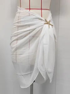 Detail view of white chiffon beach sarong featuring a gold starfish metal accessory