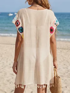 Detaillierte Rückansicht eines beigen Strand-Cover-ups mit Häkelpatchwork und Quastensaum