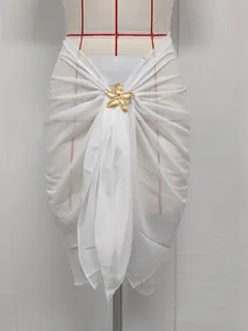 Detail of white chiffon beach sarong featuring a gold starfish metal accessory