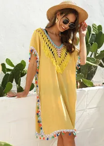 Detailed view of yellow beach cover-up with colorful tassels and crochet V-neckline