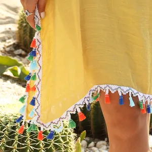 Macro view of yellow beach cover-up featuring colorful tassels and crochet trim