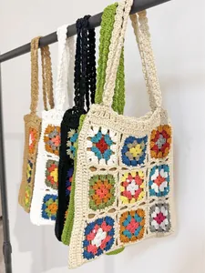 Borsa tote fatta a mano all'uncinetto con quadrati Granny colorati su rack.