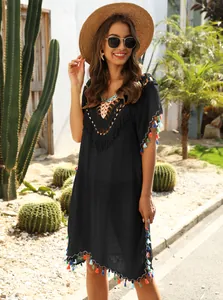 Model wearing black V-neck crochet beach cover-up with colorful tassels in desert setting