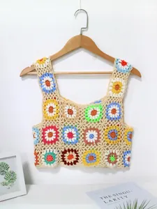 Vue détaillée du crop top en crochet fait main avec patchwork floral coloré sur cintre.