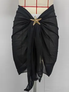 Close-up of black chiffon beach sarong featuring a decorative gold starfish buckle