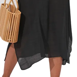 Vestido de playa negro elegante para vacaciones con tejido transparente y bolso de bambú.