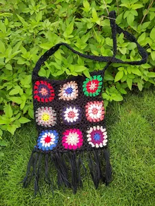 Detailed view of handmade crochet granny square bag with black fringe tassels.