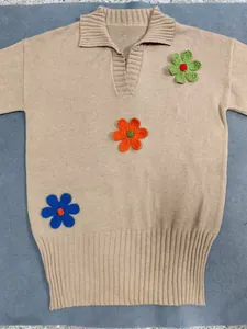 Beiges Polo-Strickkleid mit farbenfrohen Häkelblumen-Stickereien und Rippen-Details.