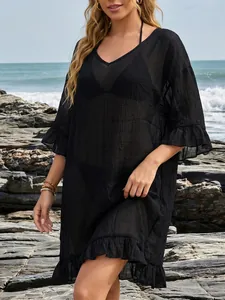 Detalle de cerca de un vestido de playa negro con cuello en V y volantes en la costa