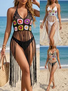 Detail view of handmade crochet beach cover-ups in black, white, and beige with long tassels.
