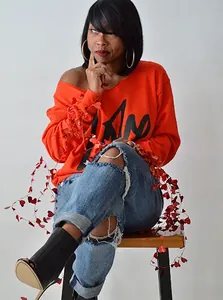 Stilvolle Nahaufnahme eines sexy orangefarbenen schulterfreien Sweatshirts mit Buchstabenaufdruck
