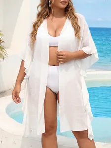 Detailed view of a white ruffle sleeve beach cover-up on a model at a sunny resort