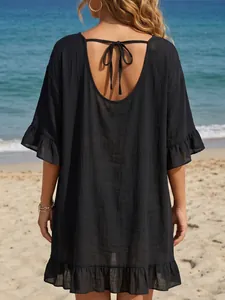 Vista trasera detallada de un vestido de playa negro con volantes en una costa soleada