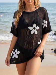 Detailed view of a black crochet beach cover-up featuring white floral knit patterns.
