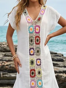 Gedetailleerd beeld van een witte strandcover-up met kleurrijke gehaakte bloempatronen.