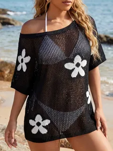 Detail of women's black crochet beach cover-up featuring white floral knit patterns