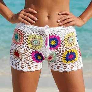 Close-up view of white handmade crochet granny square beach shorts on a female model