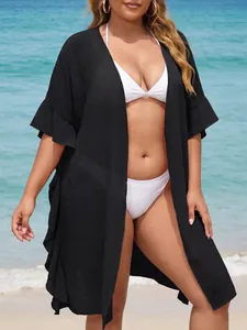 Plus size black ruffle cardigan cover-up over white bikini on sunny beach