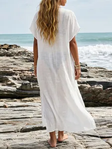 Achteraanzicht van een witte semi-transparante strandkaftan op een rotsachtige kust