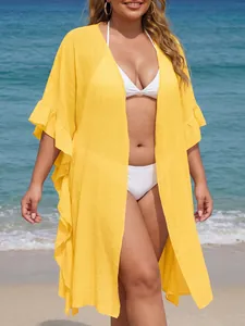 Close-up of vibrant yellow ruffle cover-up showing light textured fabric on beach