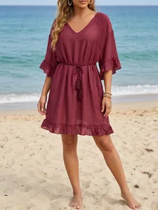 Vista frontal de un vestido de playa granate con cuello en V, volantes y cordón de borlas
