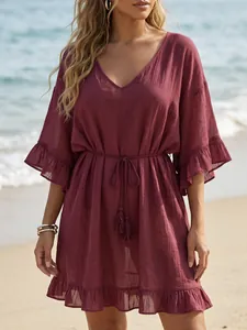 Detalle de vestido de playa granate con cuello en V, volantes y cordón con borlas.