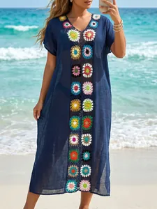 Marineblauwe gehaakte strandcover-up met kleurrijke handgemaakte bloemenpatronen op strand.