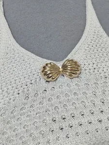 Detalle de la hebilla de concha de metal dorado en un vestido de playa de ganchillo blanco.
