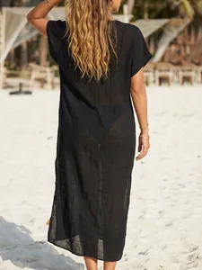 Elegante zwarte semi-transparante strandjurk van achteren gezien op een mooi wit zandstrand
