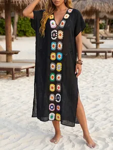 Detailweergave van zwarte strandcover-up met kleurrijke handgehaakte bloemmotieven.
