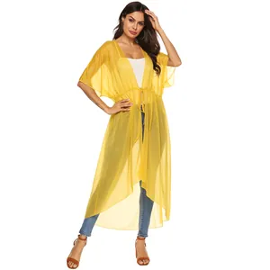 Modelo con pareo de gasa amarillo con mangas de murciélago y lazo en la cintura.