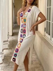 Detailweergave van een witte strandcover-up met kleurrijke gehaakte patches en zijsplitten