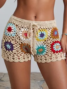 Detailed macro view of hand-crocheted granny square beach shorts with colorful floral patterns