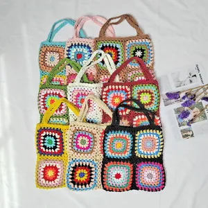 Close-up view of a colorful collection of handmade granny square crochet bags on a white surface