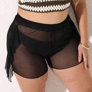 Dettaglio di pantaloncini da spiaggia neri in mesh trasparente con volant laterali
