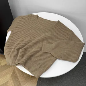 Macro view of soft brown V-neck knitted sweater texture on minimalist white table