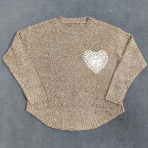 Primer plano de jersey de punto beige con detalle de bolsillo de encaje blanco de corazón