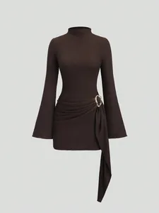 Close-up detail of textured knit fabric and gold metal buckle on a brown mini dress