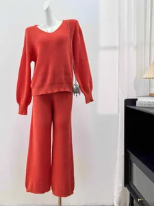 Detailed view of women's terracotta V-neck knit sweater and wide-leg pants set on mannequin