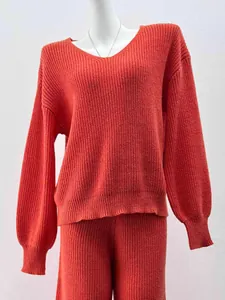 Close-up detail of burnt orange V-neck knitted sweater with matching rib-knit pants
