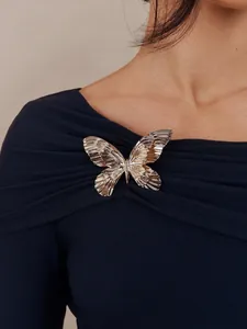Détail d'un haut bleu marine à épaules dénudées avec une grande broche papillon en métal.